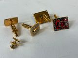 three pairs of gold cufflinks and a pair of red and black cufflinks