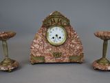 a clock sitting on top of a table next to three candles