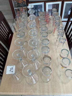 many empty glasses sitting on a table with pictures on the wall behind them