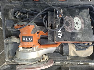 une ponceuse électrique orange et noire posée sur une boîte noire