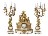 three candles and a clock sitting on a table