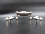 a silver bowl and three silver cups on a table