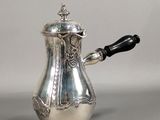 une cafetière en argent avec une poignée noire sur une table