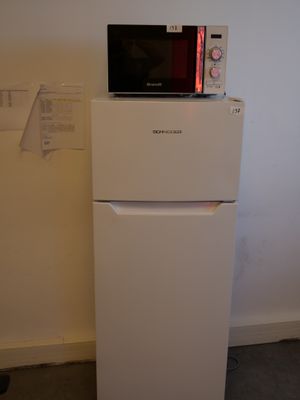 a white refrigerator with a microwave on top of it