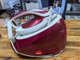 a red and white steam iron sitting on a wooden table