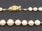 a close up of a necklace with pearls on a black surface