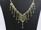a necklace with multi colored stones and gold chains on a mannequin