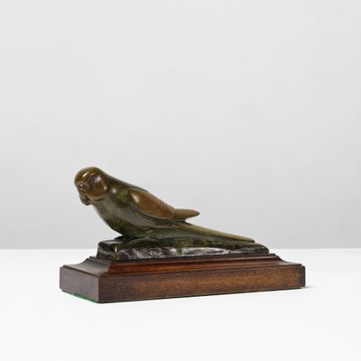 une sculpture en bronze représentant un oiseau, posée sur un socle en bois