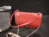 a red purse and a black purse on a black surface