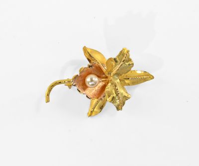 un gros plan d'une broche en forme de fleur ornée d'une perle