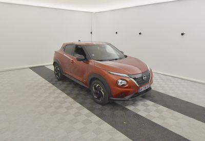 La voiture orange est garée dans le garage, sur le sol à damier.
