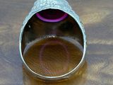 a silver ring sitting on a wooden table with a purple object in it