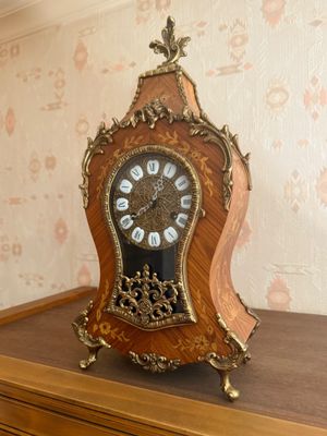 a clock on a shelf in a room with a wallpapered wall