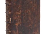 un vieux livre à la couverture brune posé sur une surface blanche