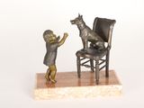 une petite statue représentant un enfant et un chien assis sur une chaise