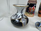 a black and white vase sitting next to a couple of empty wine glasses