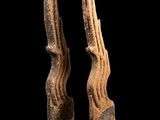 une paire de sculptures en bois sculpté posées sur des socles, sur fond noir