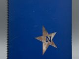 un cahier bleu sur lequel figurent la lettre « n » et une étoile sur la couverture