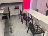 tables and chairs in a room with a red wall and a man standing in the background
