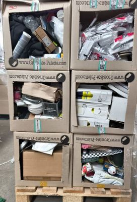 Plusieurs cartons contenant des articles divers sont empilés sur des palettes dans un entrepôt