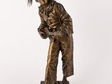 statue en bronze représentant un homme portant un chapeau et une veste, sur fond blanc