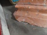 a piece of red clay sitting on the floor next to a piece of wood