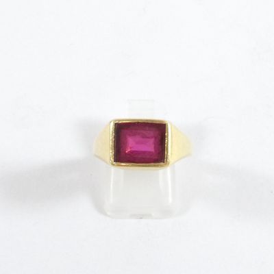 Gros plan sur une bague en or ornée d'une pierre rose