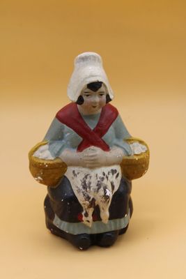 une figurine de femme assise sur une chaise