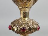 a gold cup with a red stone in it