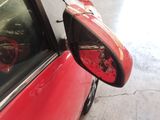 a red car parked in a garage with a mirror on it ' s side