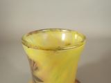 a yellow vase sitting on top of a wooden stand