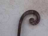 a rusted iron hook on the side of a building