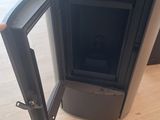 a black stove with a door open on a wooden floor