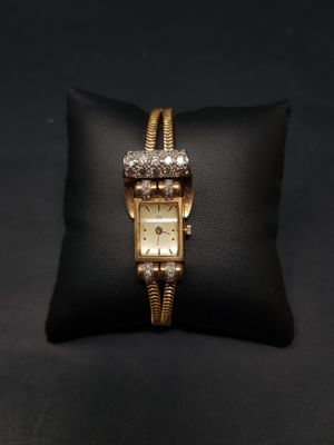 une montre en or posée sur un coussin noir, sur une surface noire