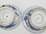 pair of blue and white porcelain cups and saucers on a white surface