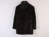 a black fur coat hanging on a white wall next to a coat rack