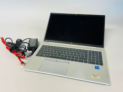 an open laptop computer sitting on top of a white table next to a charger