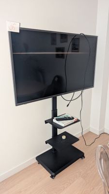 un téléviseur à écran plat posé sur un support dans le coin d'une pièce
