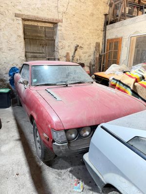 two old cars parked in a garage next to each other