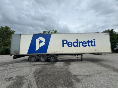 une semi-remorque blanche arborant un logo bleu et blanc, garée sur un parking