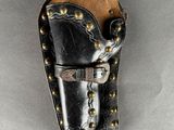 a black leather holster with brass studding and a leather belt