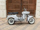 a silver motor scooter parked in front of a wooden door