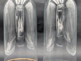 pair of clear glass vases with gold rims on a black background