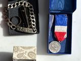 a box with a medal, a tie bar, a ring, and other items on it