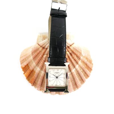 a watch sitting on top of a shell on a white surface