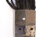 un masque en bois dont le visage est orné de plumes