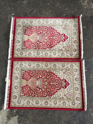 deux tapis rouges et blancs posés sur un sol en béton