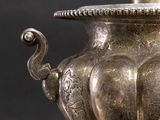 a silver vase with a candle in it sitting on a table