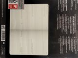 le dos d'une boîte contenant un bloc-notes, posé sur une surface blanche