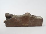 an old stone statue of a person laying down on a white surface